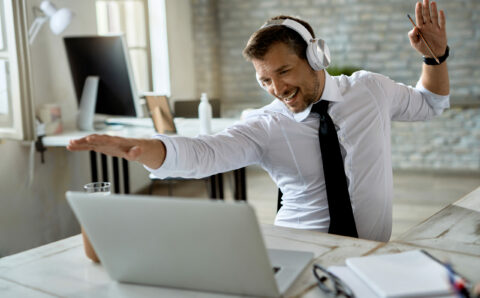 Happy businessman having fun while using laptop in the office.